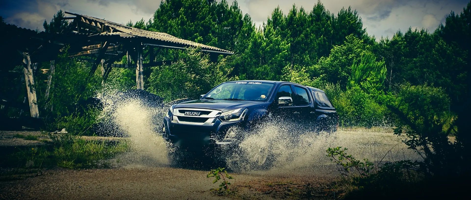 Isuzu D-Max pickup splashing through water on a bush track